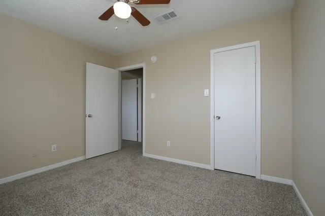 an empty room with a window and a ceiling fan