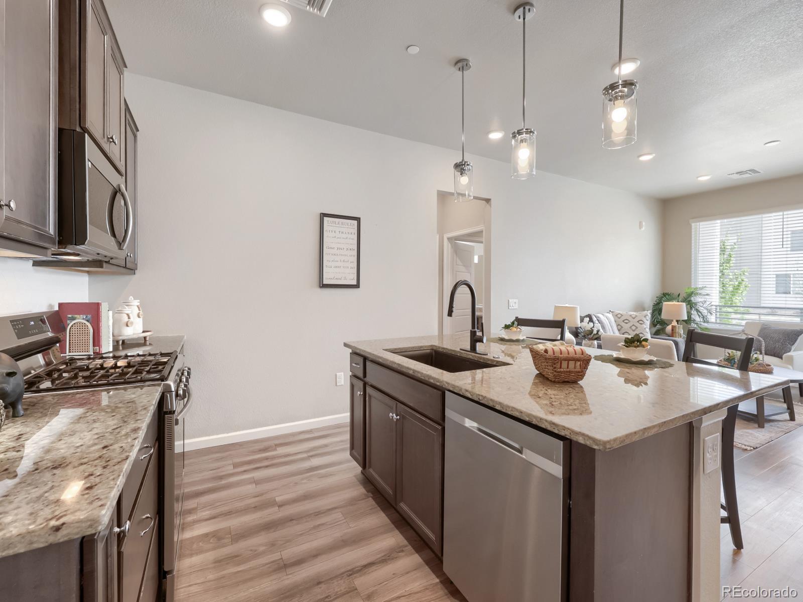 6153 North Ceylon Street, Unit 10108 Denver, CO 80249 - Photo 3 of 11 a kitchen with stainless steel appliances granite countertop a sink a stove and a wooden floors