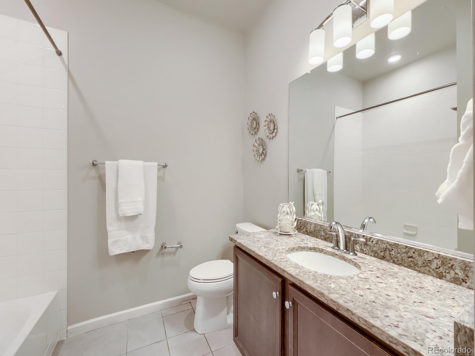 6153 North Ceylon Street, Unit 10108 Denver, CO 80249 - Photo 5 of 11 a bathroom with a granite countertop sink mirror vanity and toilet