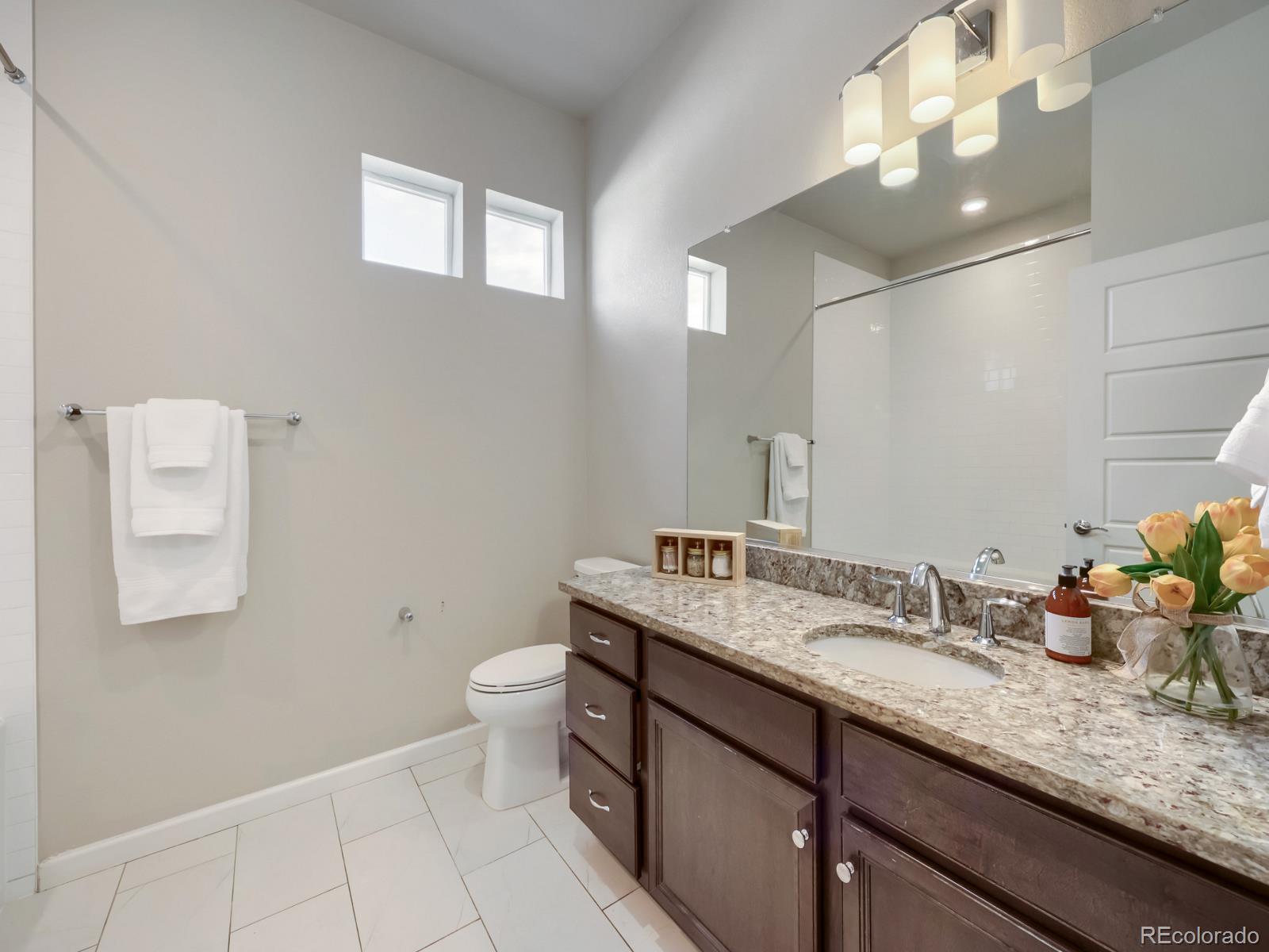 6153 North Ceylon Street, Unit 10108 Denver, CO 80249 - Photo 6 of 11 a bathroom with a granite countertop sink a toilet and a mirror