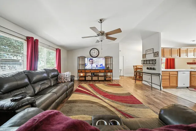 a living room with furniture kitchen view and a large window