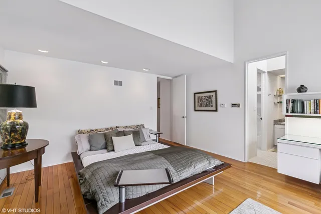 a bedroom with a bed a dresser and a large window