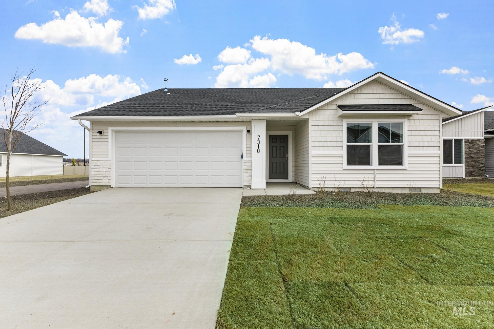 Single story home with driveway, roof with shingles, a garage, and a front yard