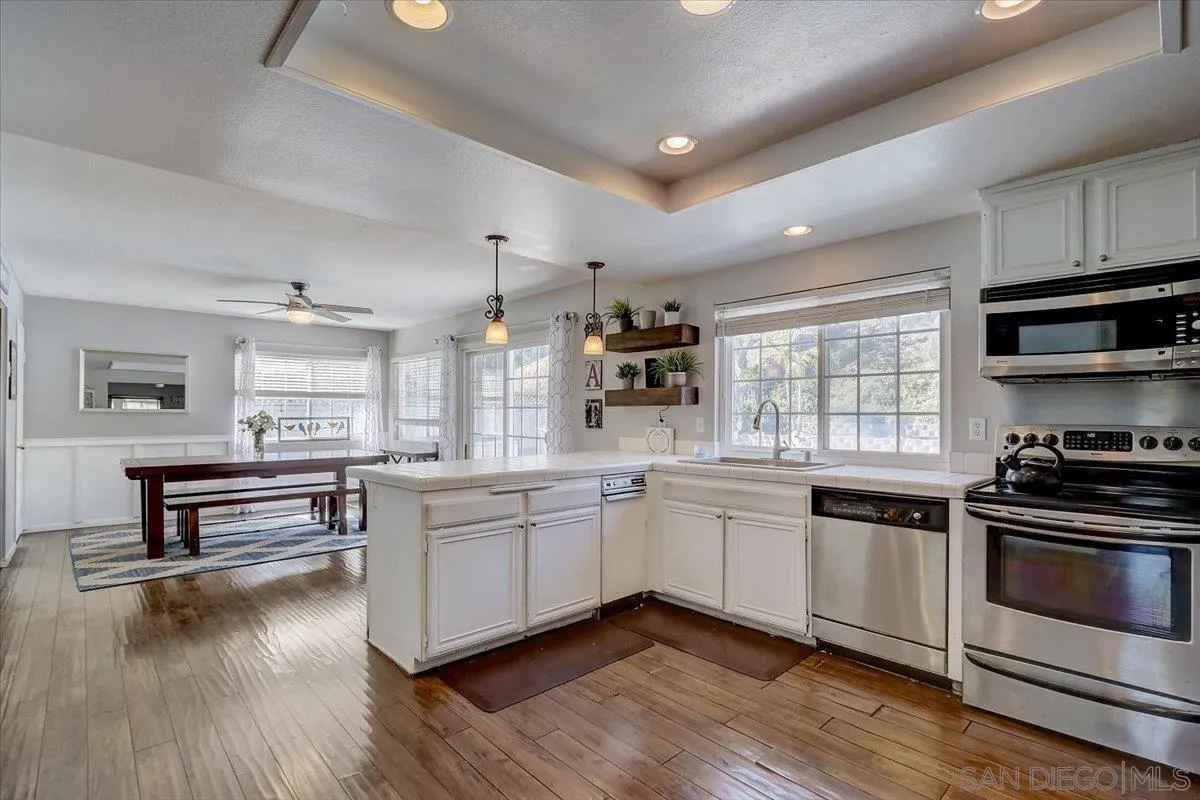 4094 Tambor Road San Diego, CA 92124 - Photo 18 of 49 a kitchen with stainless steel appliances white cabinets and wooden floor