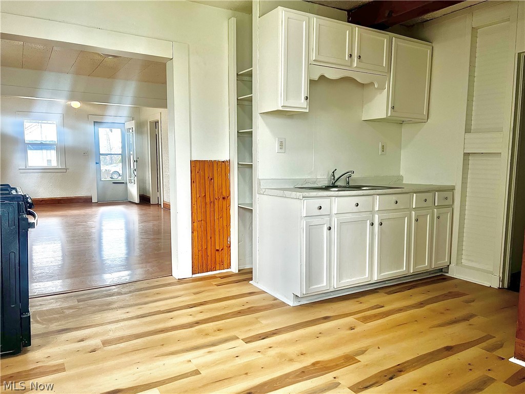 67 Forbes Road Bedford, OH 44146 - Photo 6 of 20 Kitchen with white cabinetry, light countertops, gas stove, and light wood-type flooring