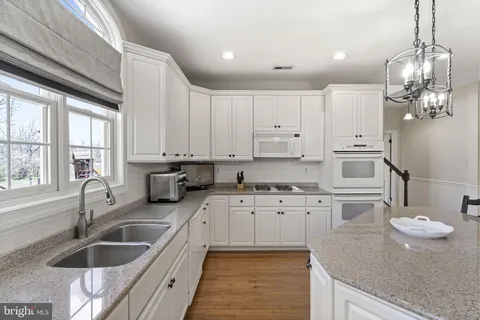 a kitchen with granite countertop a sink a stove and cabinets