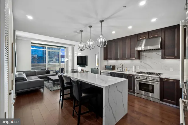 a kitchen with stainless steel appliances granite countertop a stove top oven a sink dishwasher a dining table and chairs with wooden floor