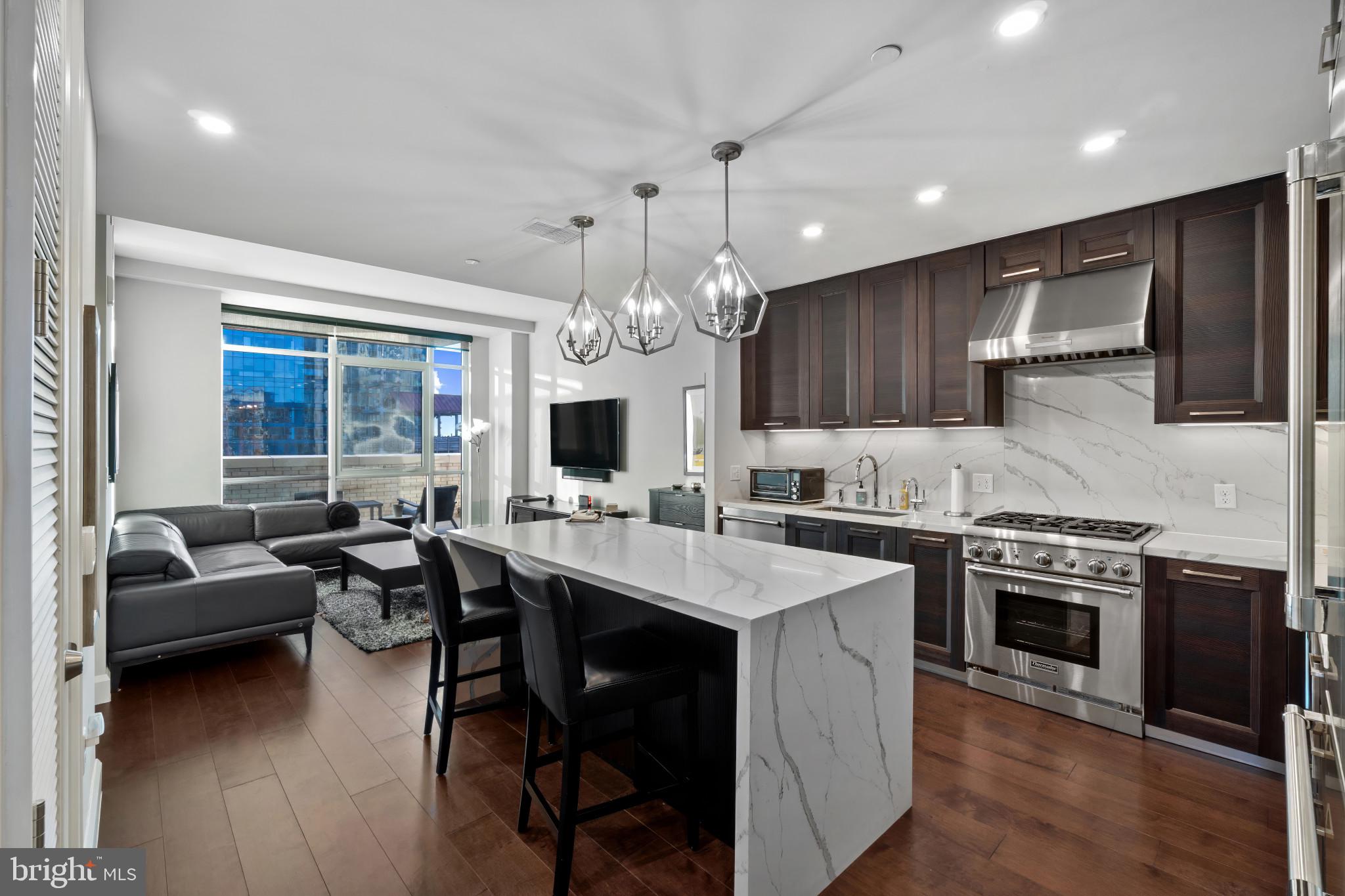 a kitchen with stainless steel appliances granite countertop a stove top oven a sink dishwasher a dining table and chairs with wooden floor