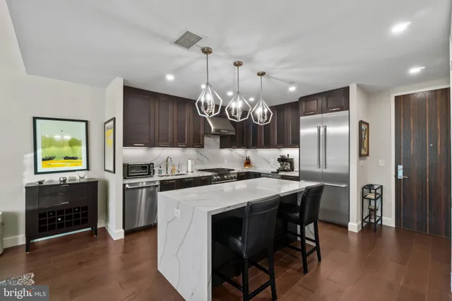 a kitchen with stainless steel appliances granite countertop a stove refrigerator and a fireplace with wooden floor