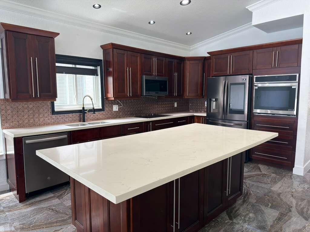 4572 Southwest 14th Street Deerfield Beach, FL 33442 - Photo 16 of 81 a kitchen with stainless steel appliances wooden cabinets a sink and a refrigerator