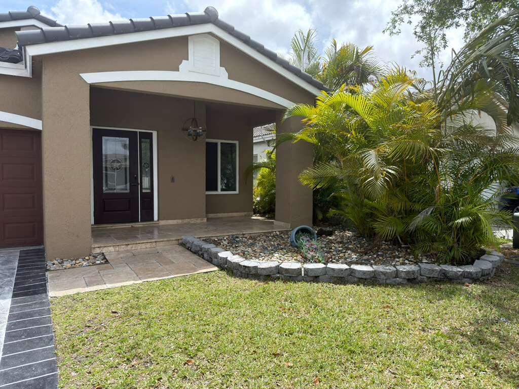 4572 Southwest 14th Street Deerfield Beach, FL 33442 - Photo 5 of 81 a view of a house with a small yard plants and large tree