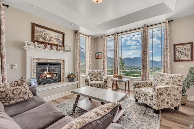 2543 East 700 South Springville, UT 84663 - Photo 18 of 73 Living room with a mountain view, wood finished floors, a glass covered fireplace, and a tray ceiling