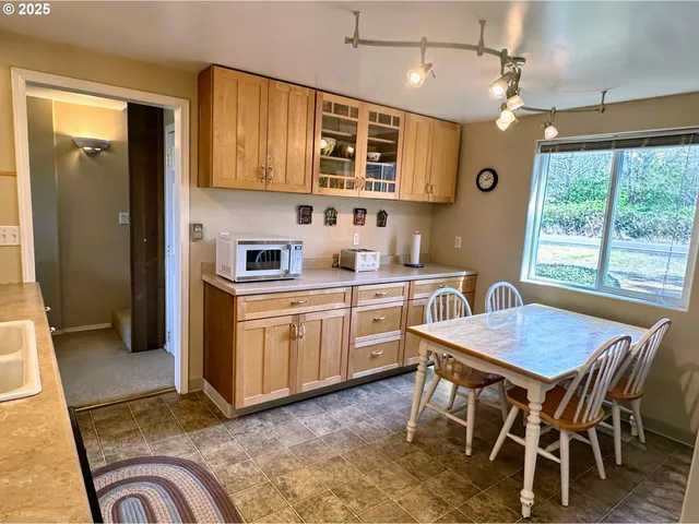 a kitchen with a stove a sink dishwasher a dining table and chair with wooden floor