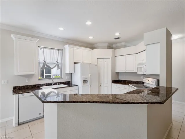 a kitchen with granite countertop kitchen island stainless steel appliances a sink and a refrigerator