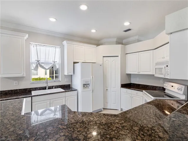 a kitchen with stainless steel appliances kitchen island granite countertop a refrigerator and a sink
