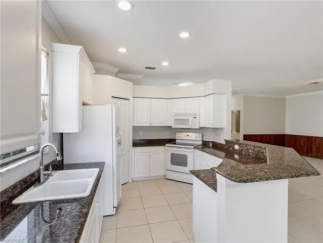 a kitchen with kitchen island granite countertop a sink stove and refrigerator