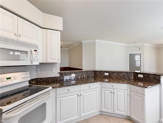a kitchen with granite countertop white cabinets and black appliances
