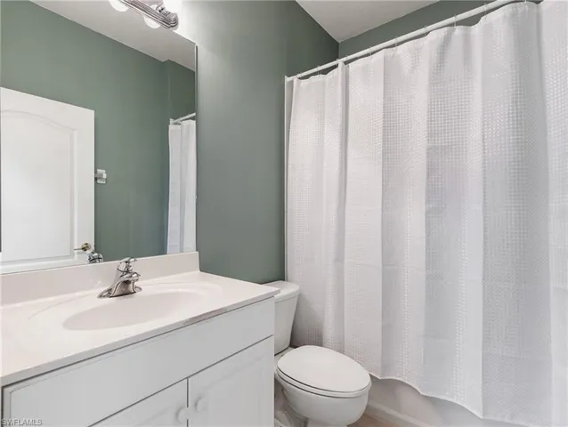 a bathroom with a sink a toilet and shower curtain