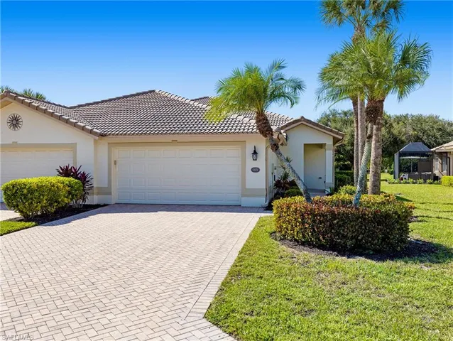 a front view of a house with a garden and palm trees