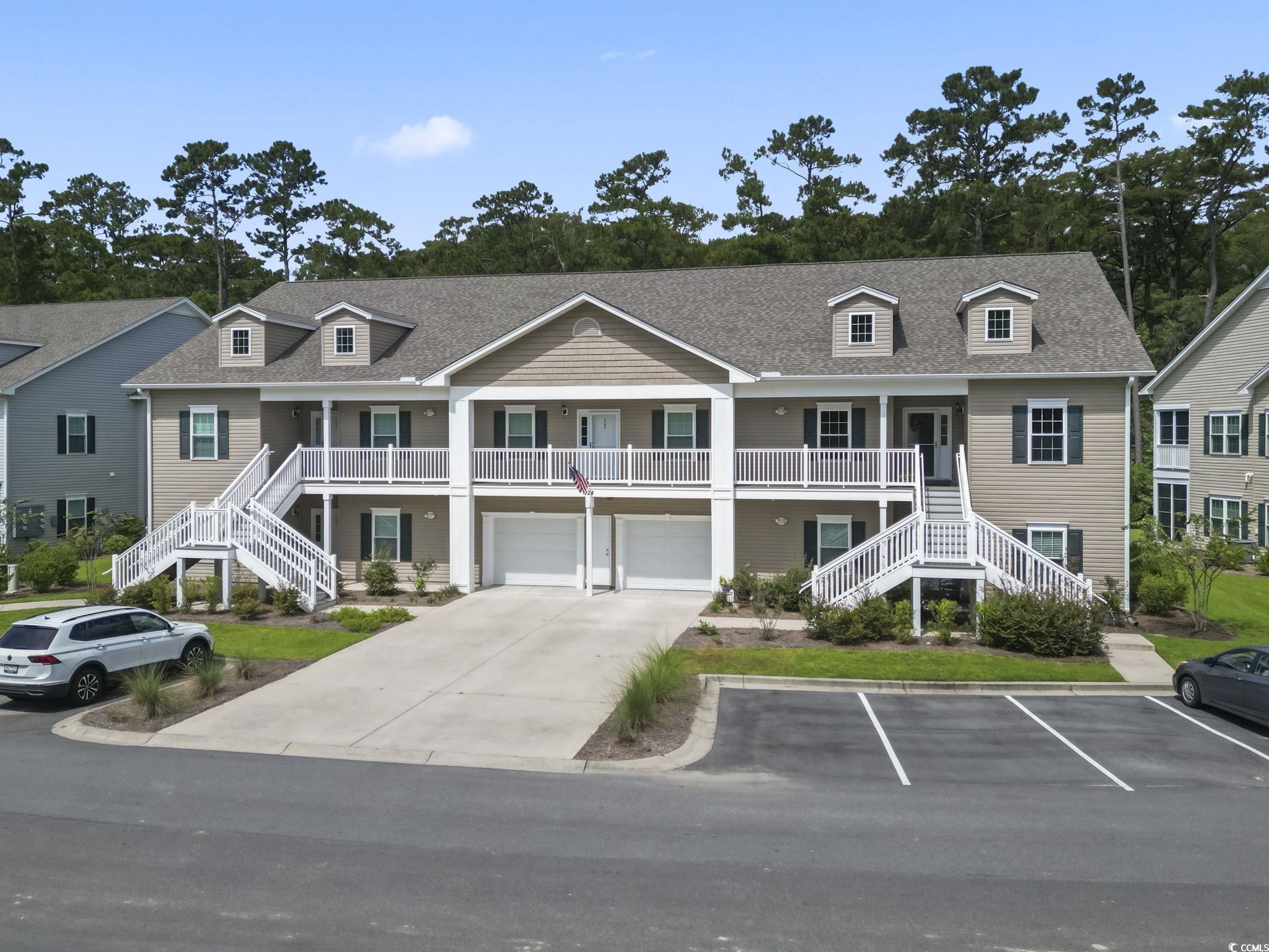 Raised beach house with stairs, covered porch, an attached garage, and driveway