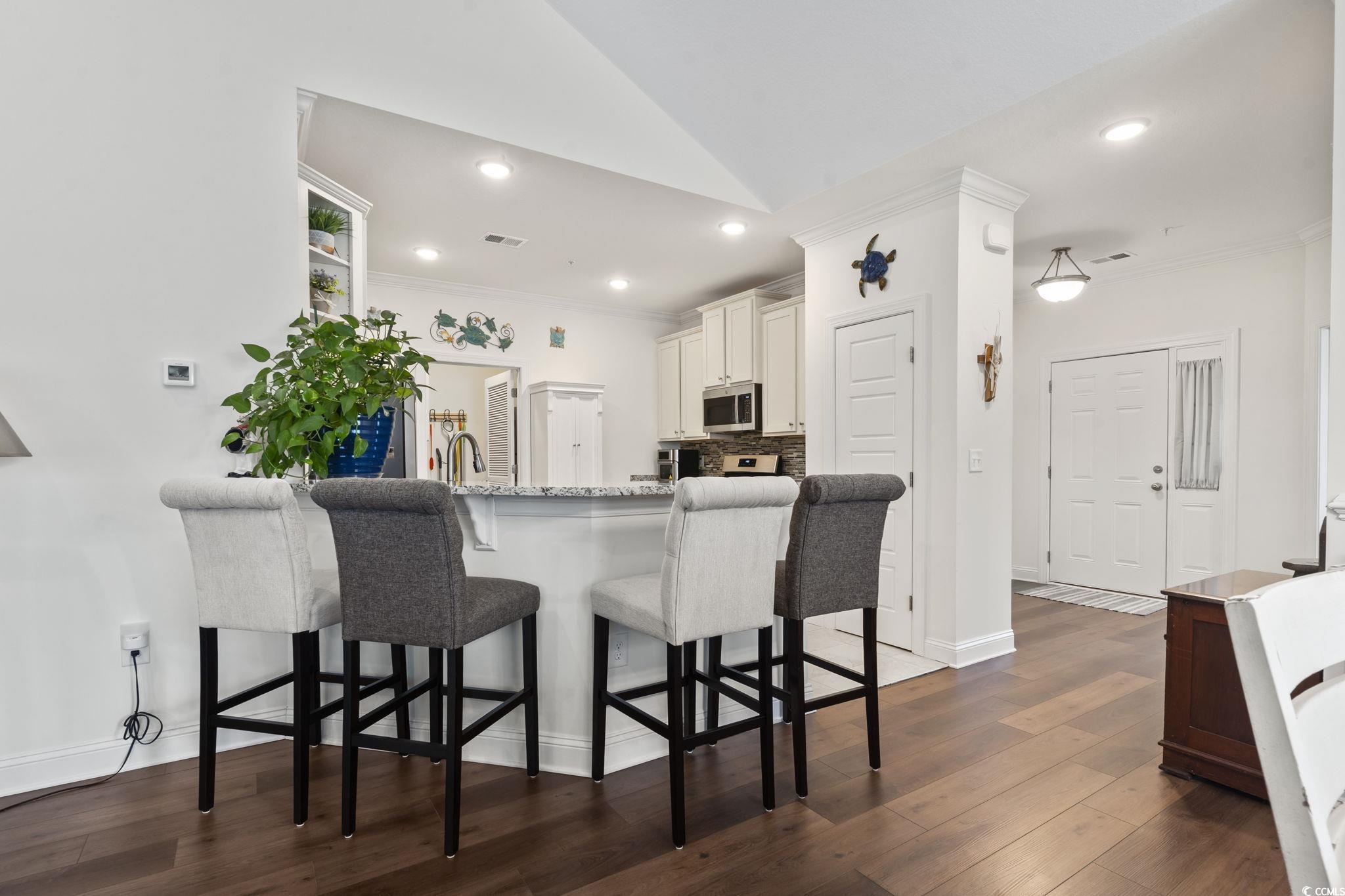 924 Jackline Place, Unit 201 Murrells Inlet, SC 29576 - Photo 4 of 35 Kitchen featuring light stone counters, dark wood-style flooring, a breakfast bar area, recessed lighting, and white cabinets