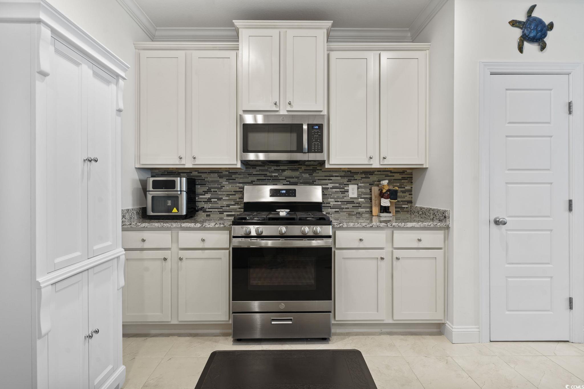 924 Jackline Place, Unit 201 Murrells Inlet, SC 29576 - Photo 7 of 35 Kitchen featuring stainless steel appliances, decorative backsplash, light stone countertops, and ornamental molding