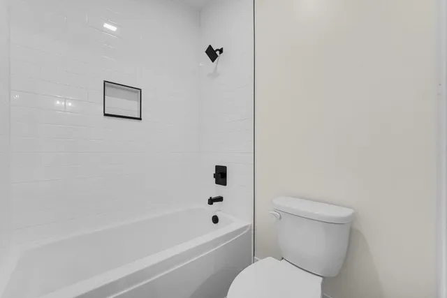 a white toilet sitting next to a bath tub