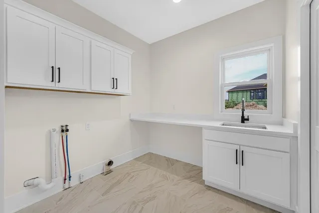 a kitchen with white cabinets and sink