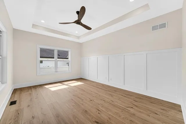 a view of empty room with wooden floor and ceiling fan