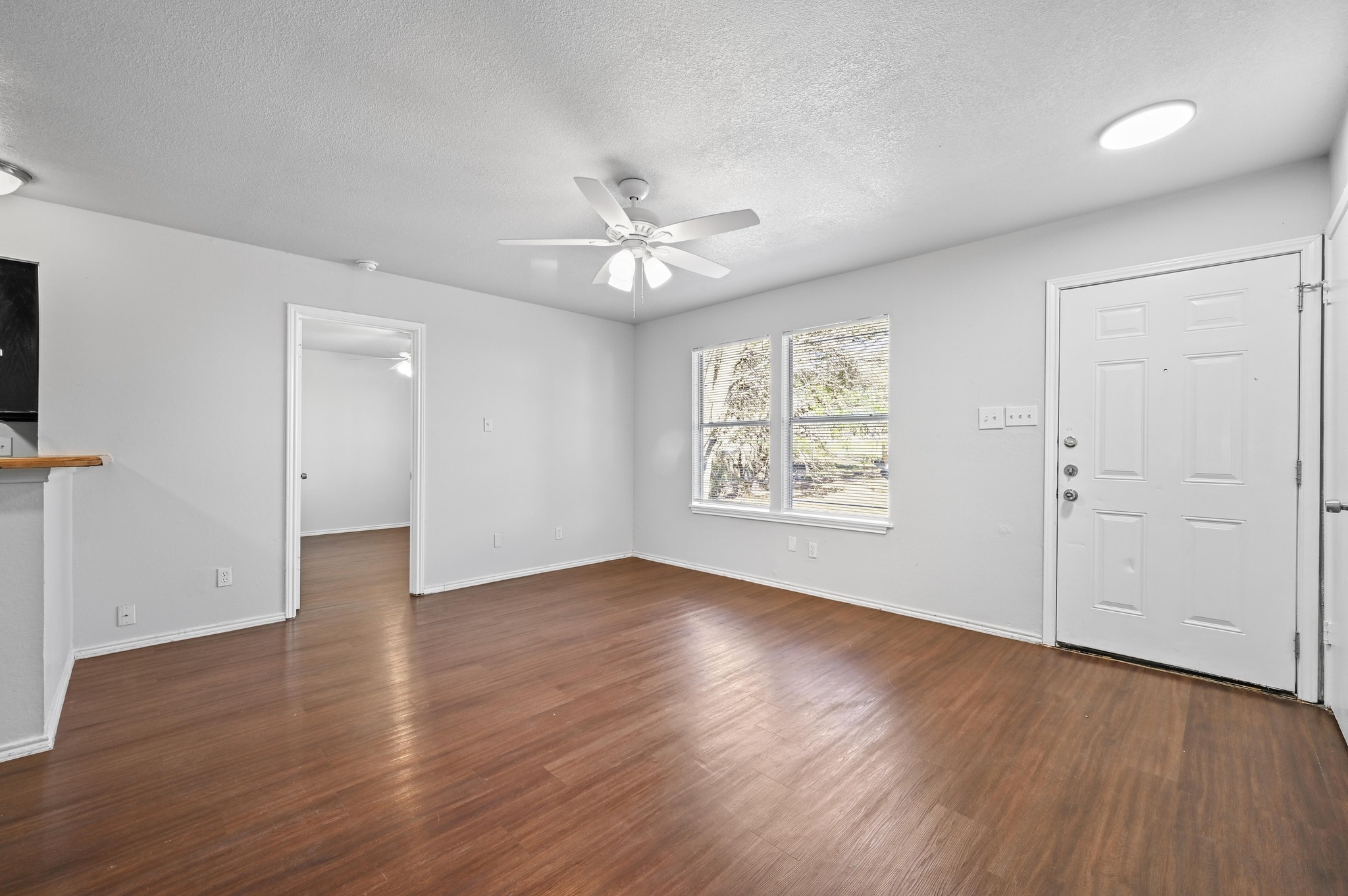 5303 Spring Meadow Road Austin, TX 78744 - Photo 5 of 20 an empty room with wooden floor chandelier fan and windows