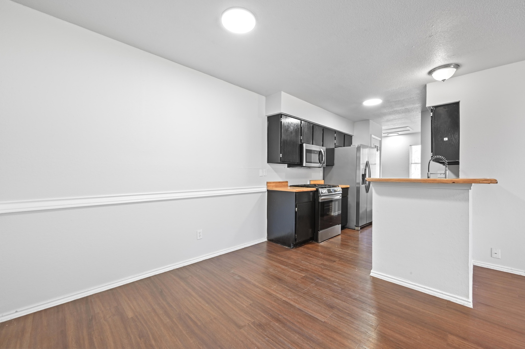 5303 Spring Meadow Road Austin, TX 78744 - Photo 8 of 20 a kitchen with a sink wooden floor and stainless steel appliances