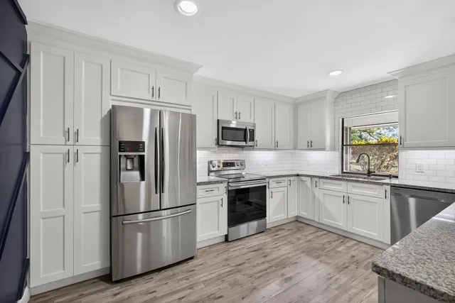 a kitchen with stainless steel appliances granite countertop a refrigerator stove and microwave