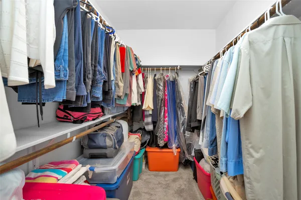 a view of walk in closet with clothes and shoes