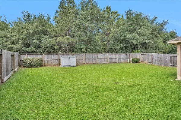 a view of a backyard with a large tree and wooden fence