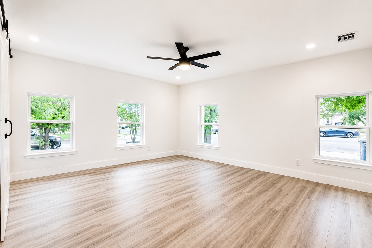 Smooth wood-look flooring and multiple windows create a clean, minimalist interior aesthetic.