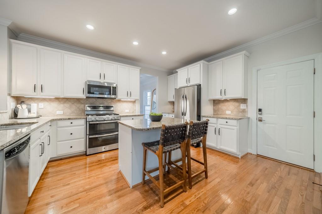 7604 Birchwalk Drive Huntersville, NC 28078 - Photo 15 of 37 a kitchen with stainless steel appliances kitchen island granite countertop a refrigerator a stove top oven a sink dishwasher and white cabinets with wooden floor