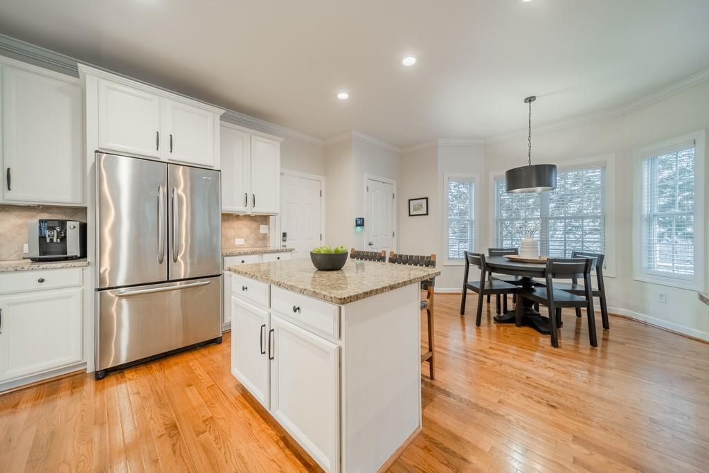 7604 Birchwalk Drive Huntersville, NC 28078 - Photo 17 of 37 a kitchen with stainless steel appliances granite countertop a stove a refrigerator a dining table and chairs with wooden floors