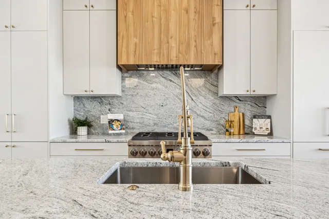 a kitchen with stainless steel appliances granite countertop a sink a stove and a microwave oven with white cabinets