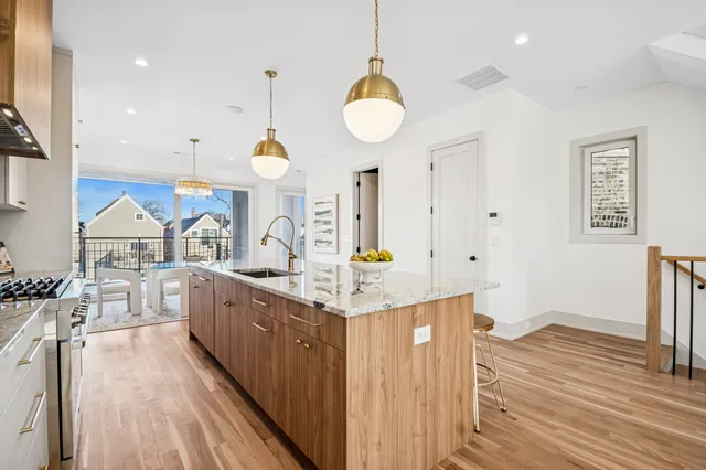 a kitchen with granite countertop a stove oven a sink dishwasher and white cabinets with wooden floor