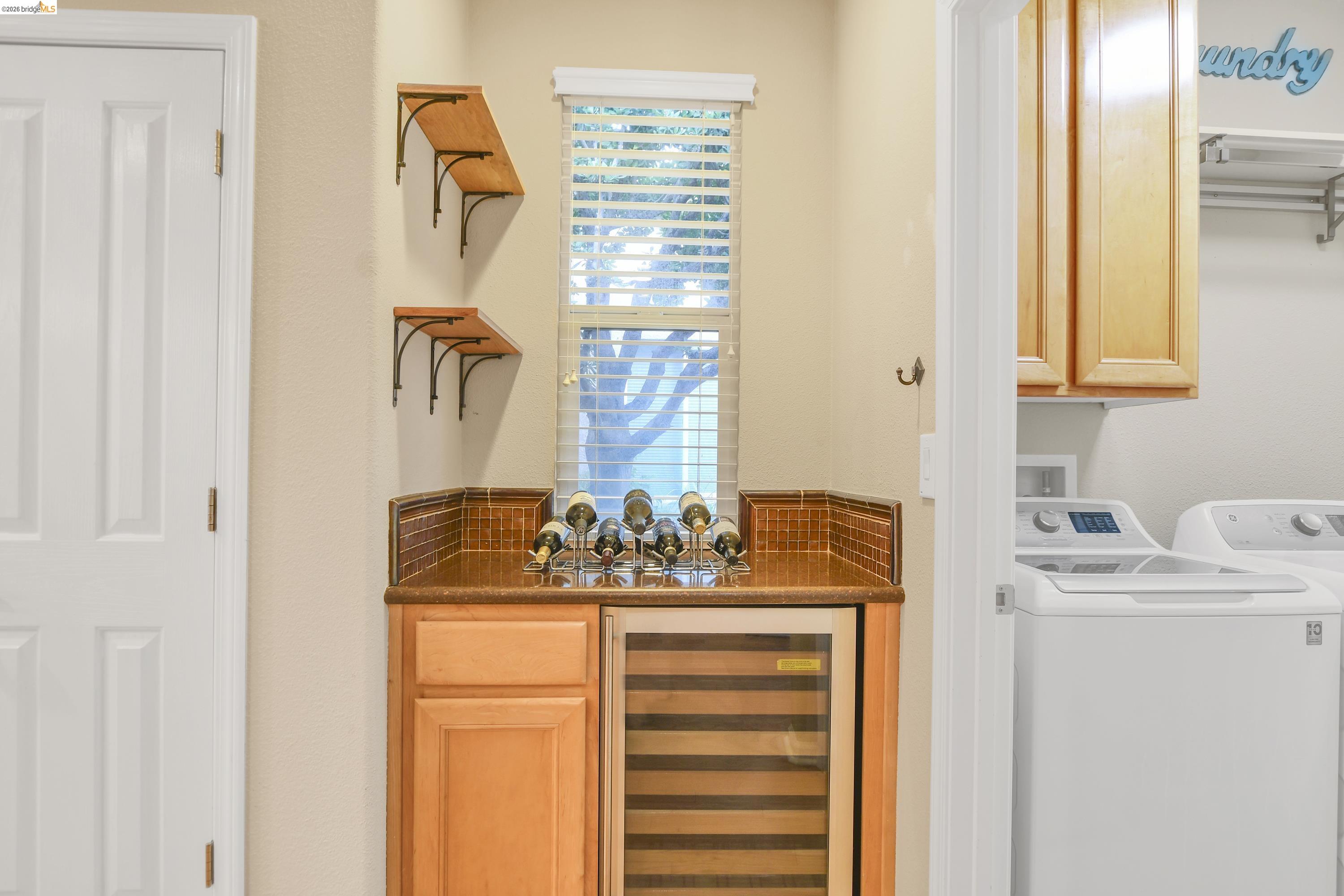 342 Desert Forest Court Rio Vista, CA 94571 - Photo 25 of 40 Indoor bar featuring beverage cooler, separate washer and dryer, light brown cabinetry, and dark stone counters