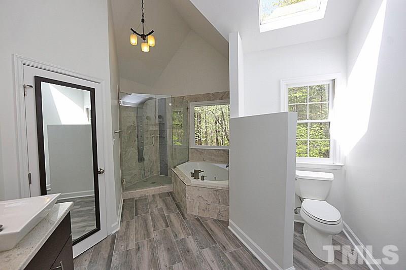 12317 Glenlivet Way Raleigh, NC 27613 - Photo 17 of 25 a bathroom with a granite countertop toilet a sink and bathtub