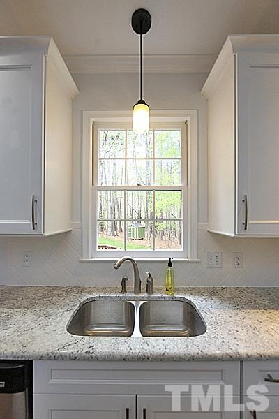 12317 Glenlivet Way Raleigh, NC 27613 - Photo 6 of 25 a kitchen with granite countertop a sink a window and cabinets