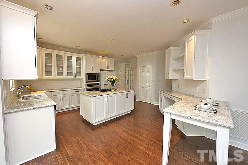 12317 Glenlivet Way Raleigh, NC 27613 - Photo 8 of 25 a kitchen with a stove top oven a sink dishwasher and a refrigerator with wooden floor