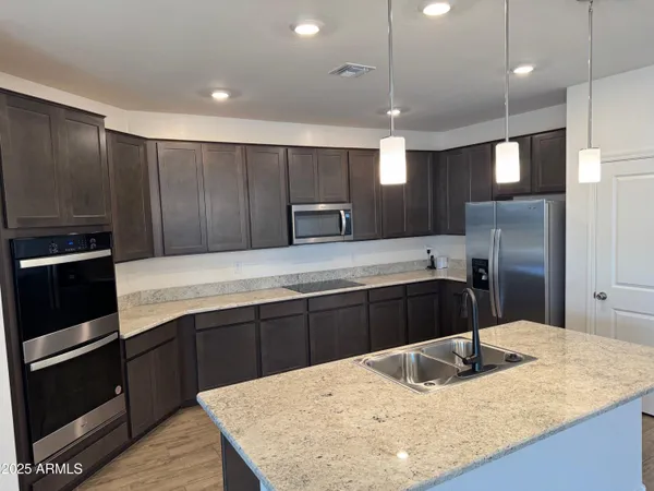 a kitchen with kitchen island granite countertop wooden cabinets and refrigerator