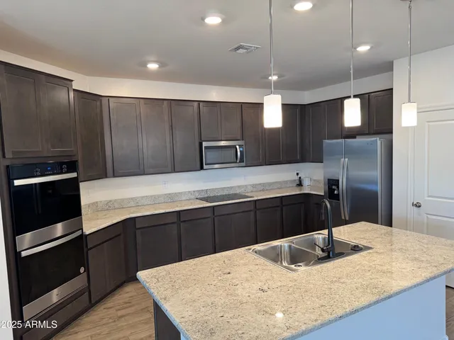 a kitchen with kitchen island granite countertop wooden cabinets and refrigerator