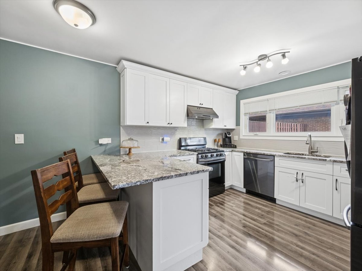 1220 Fulton Drive Streamwood, IL 60107 - Photo 6 of 18 a kitchen with stainless steel appliances kitchen island granite countertop a table chairs sink and cabinets