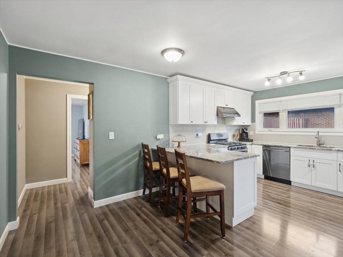 1220 Fulton Drive Streamwood, IL 60107 - Photo 7 of 18 a kitchen with stainless steel appliances a dining table chairs stove refrigerator and cabinets