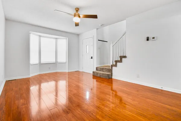 a view of empty room with wooden floor and fan