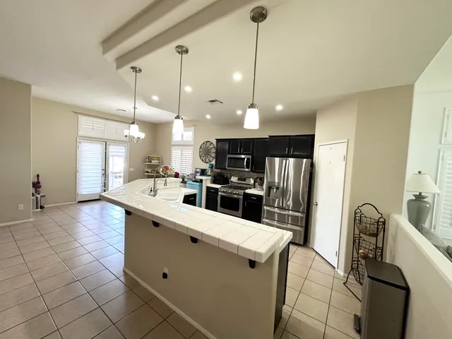 a kitchen with stainless steel appliances kitchen island granite countertop a stove top oven a sink a dining table and chairs