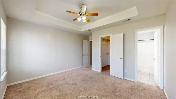 an empty room with closet and a ceiling fan